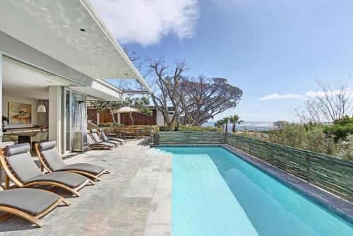 a swimming pool with chairs and a house at Blinkwater Villa in Cape Town