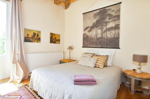 a bedroom with a white bed with a large painting on the wall at Cahors - Lot - Les Lumières du Causse - Domaine en pierres blanches avec vue sur les causses in Bellefont-La Rauze