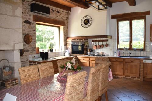 uma cozinha com uma mesa com cadeiras e um relógio na parede em LES 2 CHENES em Les Riffes