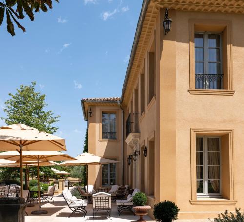 a patio with chairs and umbrellas in front of a building at Villa Saint-Ange in Aix-en-Provence