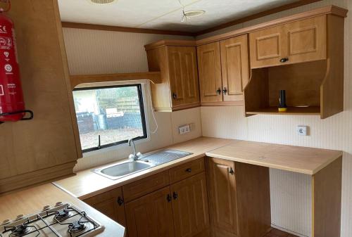 a kitchen with wooden cabinets and a sink and a window at Chalet Westmoreland in De Pol