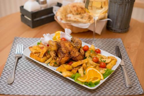 a plate of food with chicken and french fries and a glass of wine at Seva Hotel Health Club in Campina