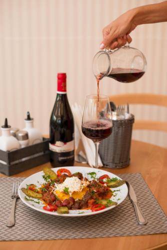 a person pouring red wine into a plate of food at Seva Hotel Health Club in Campina