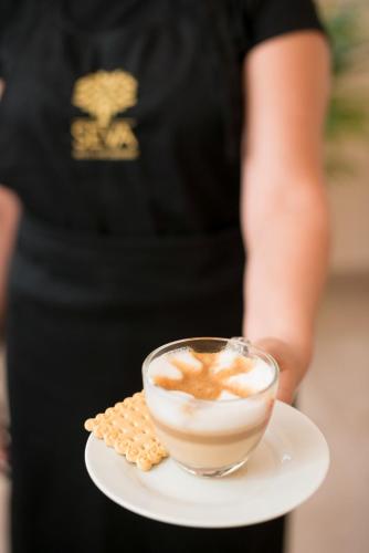a woman holding a plate with a cup of coffee and crackers at Seva Hotel Health Club in Campina