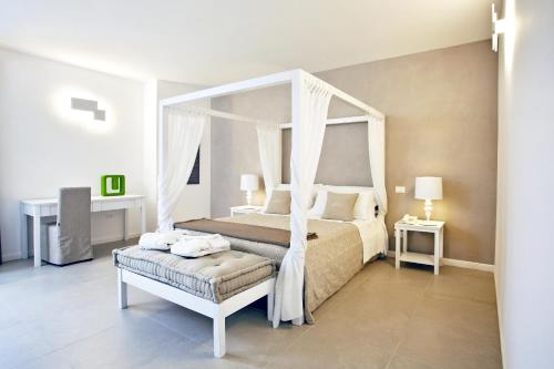 a white bedroom with a canopy bed and a bench at Giardino Dei Pini - Boutique Hotel in Alliste