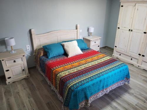 1 dormitorio con 1 cama con una manta colorida y 2 mesitas de noche en ZARAPITO en Chiclana de la Frontera