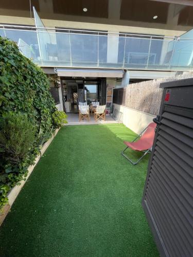 a house with a yard with green grass at Beach flat with garden in Castelldefels