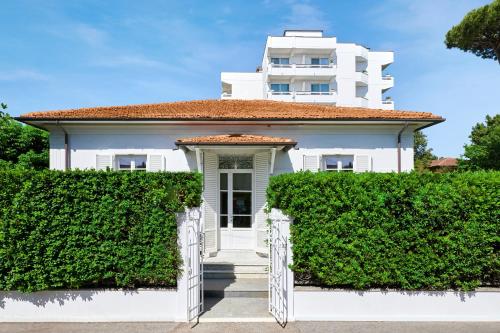 a white house with a hedge in front of it at Mondial Resort & Spa in Marina di Pietrasanta