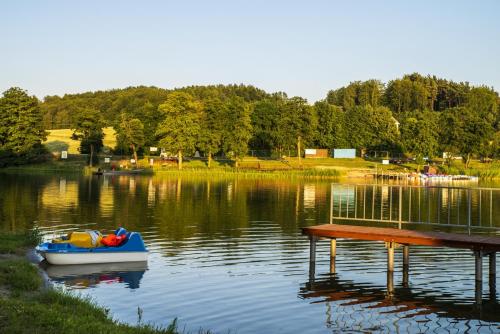 a small boat sitting next to a dock on a lake at U Lipińskich - Dom nad jeziorem in Ostrzyce