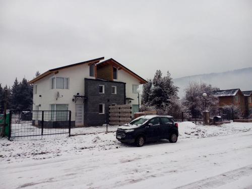 a black suv parked on a snowy road in front of a house at ALBANTA Lago Puelo in Lago Puelo
