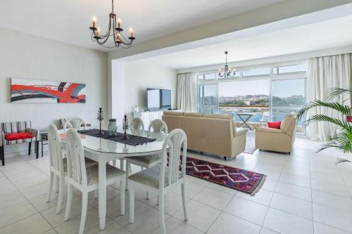 uma sala de jantar e sala de estar com mesa e cadeiras em Stunning - Seafront 3-Bedroom 6th Floor em Sliema