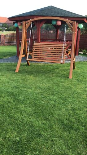 a wooden gazebo with a swing in the grass at Agroturystyka "Zielone Zacisze" in Łagów