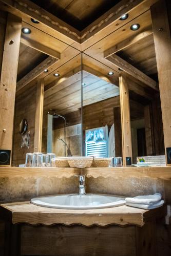 une salle de bain avec un lavabo et un grand miroir dans l'établissement Les Chalets de la Serraz, à La Clusaz
