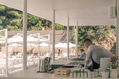 a man standing at a counter in a restaurant at Radisson Resort Plaza Skiathos in Kanapitsa
