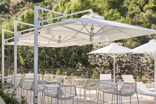 a group of tables and chairs under a white umbrella at Radisson Resort Plaza Skiathos in Kanapitsa