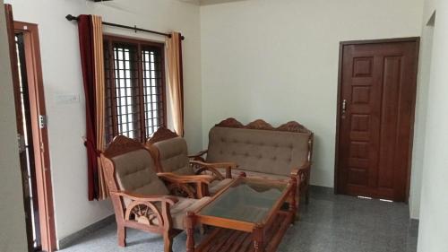a living room with two chairs and a door at Tejus Home Stay in Alleppey
