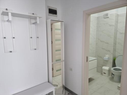a white bathroom with a toilet and a mirror at Luxury New and Modern Apartments in Mamaia Nord
