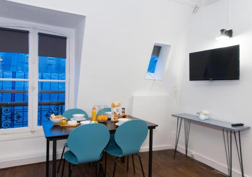 uma sala de jantar com uma mesa e cadeiras azuis em Sweet Inn - Saint Honore em Paris
