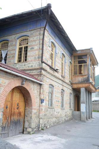 a large stone building with a wooden door and a balcony at Ali Ancient House 555 in Sheki