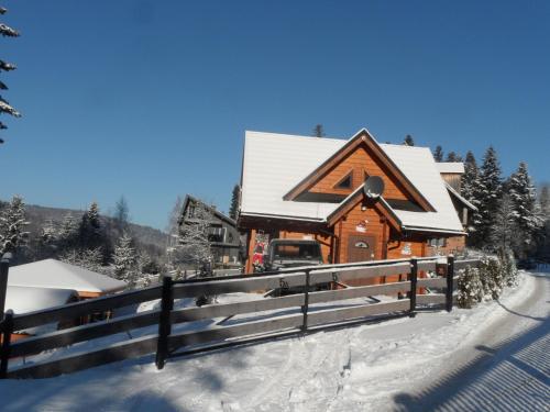 a log cabin in the snow with a fence at Domki pod Pilskiem in Korbielów