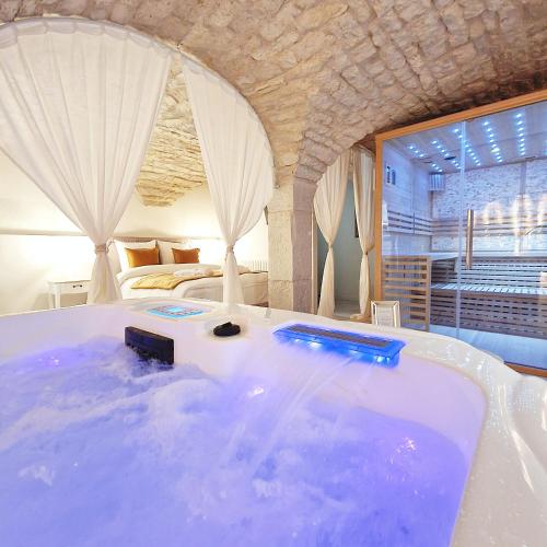 - une grande baignoire dans une chambre avec un lit dans l'établissement La Dolce Vita Spa privatif, à Dole