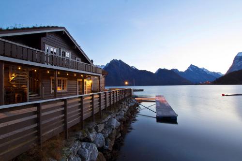 Sagafjord Hotel - by Classic Norway Hotels في Sæbø: كابينة على بحيرة وجبال في الخلفية