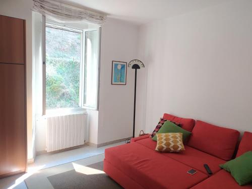 a red couch in a living room with a window at MARE,BIKING, CLIMBING in Finale Ligure