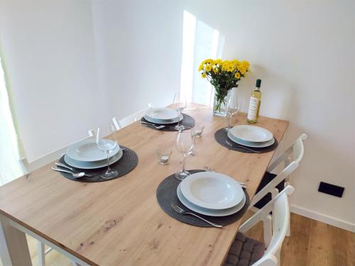 a wooden table with plates and wine glasses on it at FeWo Wildflecken - Ferienwohnung Rhön Neubau 2021 in Wildflecken