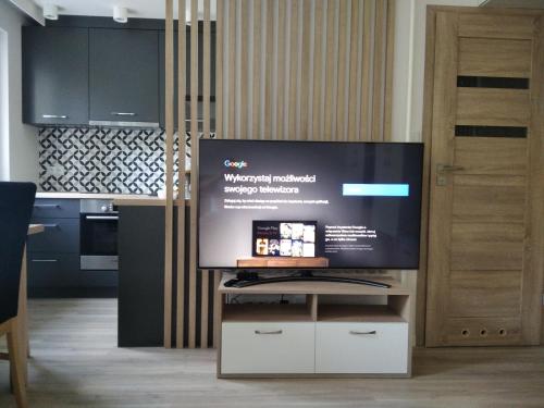 a flat screen tv sitting on a stand in a kitchen at Apartament ZDRÓJ in Busko-Zdrój