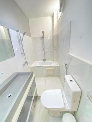 a white bathroom with a toilet and a sink at Appartement haut standing idéalement situé à Dakar in Dakar