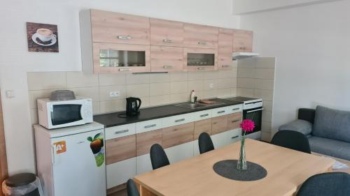 a small kitchen with a table and a refrigerator at Penzion Dominik in Železná Ruda