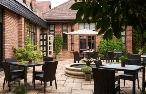 a patio with tables and chairs and a fountain at Careys Manor Hotel & SenSpa in Brockenhurst