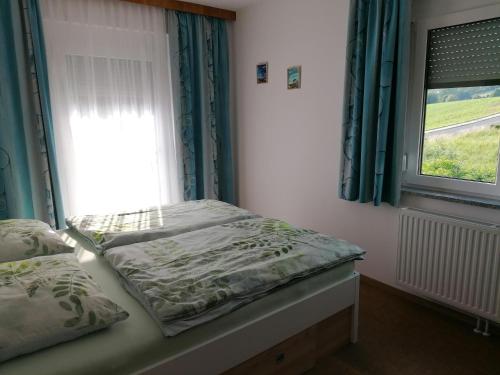 a small bedroom with a bed with a window at FEWO an der Brücke in Stubenberg