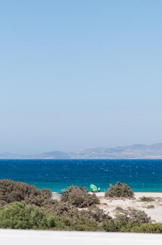 a beach with a green umbrella and the ocean at Stremma Naxos in Aliko Beach