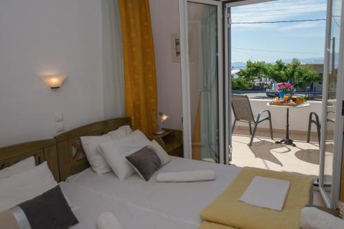 a bedroom with a bed and a balcony with a table at Hotel Avra in Néa Epídhavros