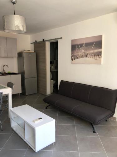un salon avec un canapé noir et une table dans l'établissement BEAU T2 RIVE GAUCHE ETAT NEUF CLIMATISE, à Palavas-les-Flots