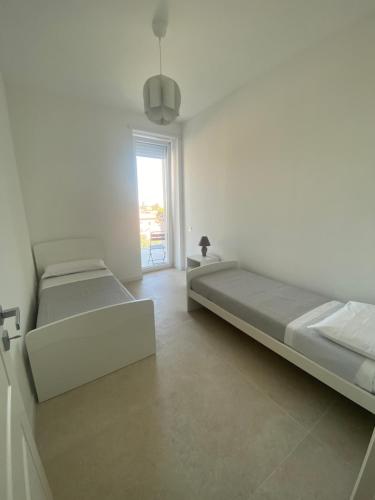 een witte kamer met 2 bedden en een raam bij Carlino's Home in Salerno