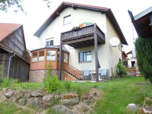 une maison avec un balcon et des chaises dans la cour dans l'établissement Ferienwohnung Vreni, à Gersfeld