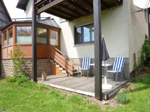 a wooden deck with two chairs and an umbrella at Ferienwohnung Vreni in Gersfeld