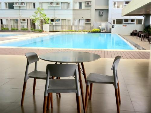 une table et des chaises devant une piscine dans l'établissement Davao Avida Towers, à Davao