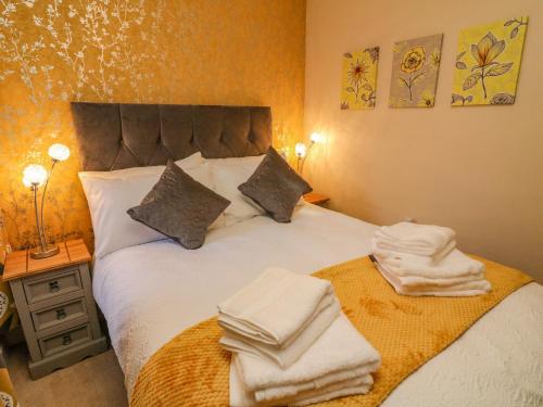 een slaapkamer met een bed met handdoeken erop bij Dairy Cottage in Carnforth