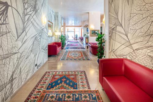een lobby met een rode bank en een tapijt bij Hotel Royal in Bibione