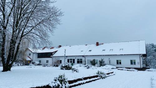 a large white house with snow on the ground at Gospodarstwo Agroturystyczne Zasadkowe Bory in Rogowo