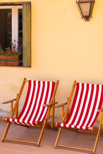 two red and white striped chairs sitting next to a building at Albergo Villa San Michele in Greve in Chianti