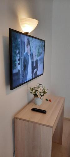 a flat screen tv hanging on a wall with a table at Cozy House Decebal in Cluj-Napoca