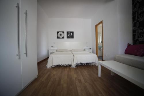 a white bedroom with a bed and a couch at Hostal Boutique Los Geranios del Pinar in Torremolinos