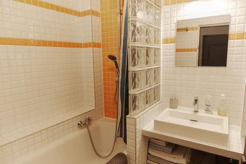 une salle de bain blanche avec un lavabo et une douche dans l'établissement Cozy 2-Pièces au Coeur du Haut-Marais, à Paris