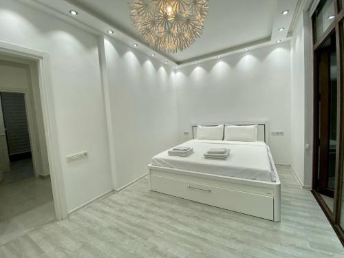a white bedroom with a bed and a chandelier at European Village Old Villa 6 in Gonio