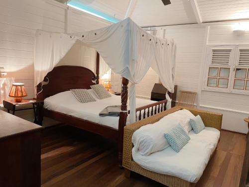 - une chambre avec deux lits et un lit à baldaquin dans l'établissement Bungalow Karaib Lodge, à Saint-François