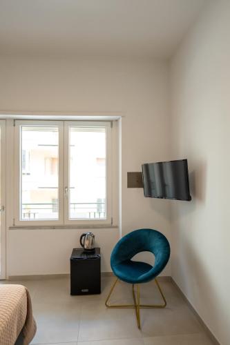 a room with a blue chair and a television at Relais Vittorio Veneto - Luxotel & Apartotel in Salerno
